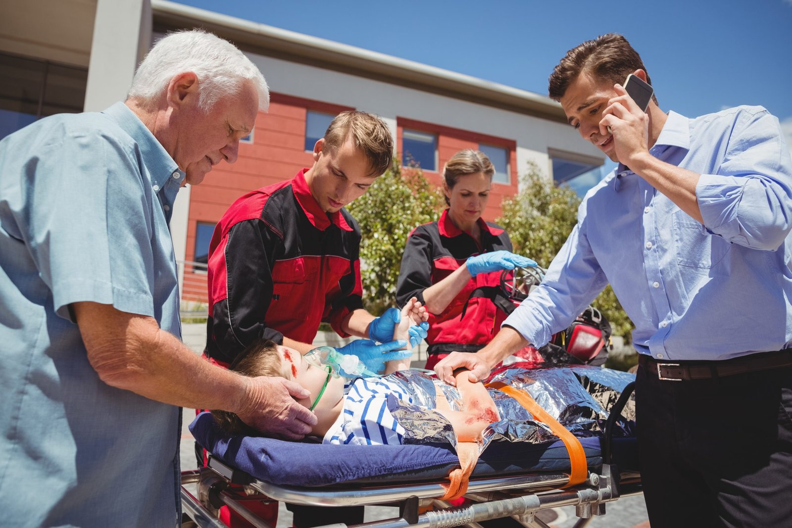 Paramedics examining injured boy on street